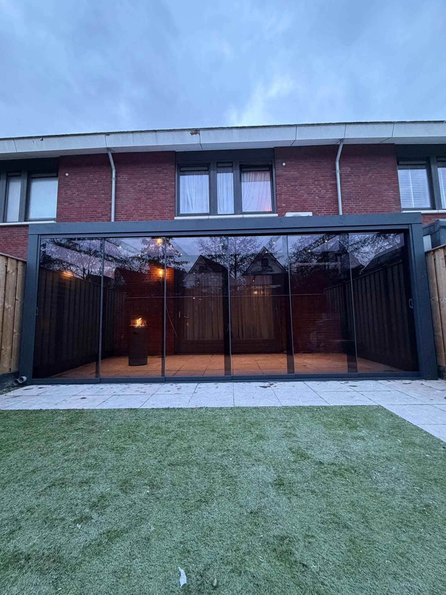 Veranda met glazen schuifwanden in de avond